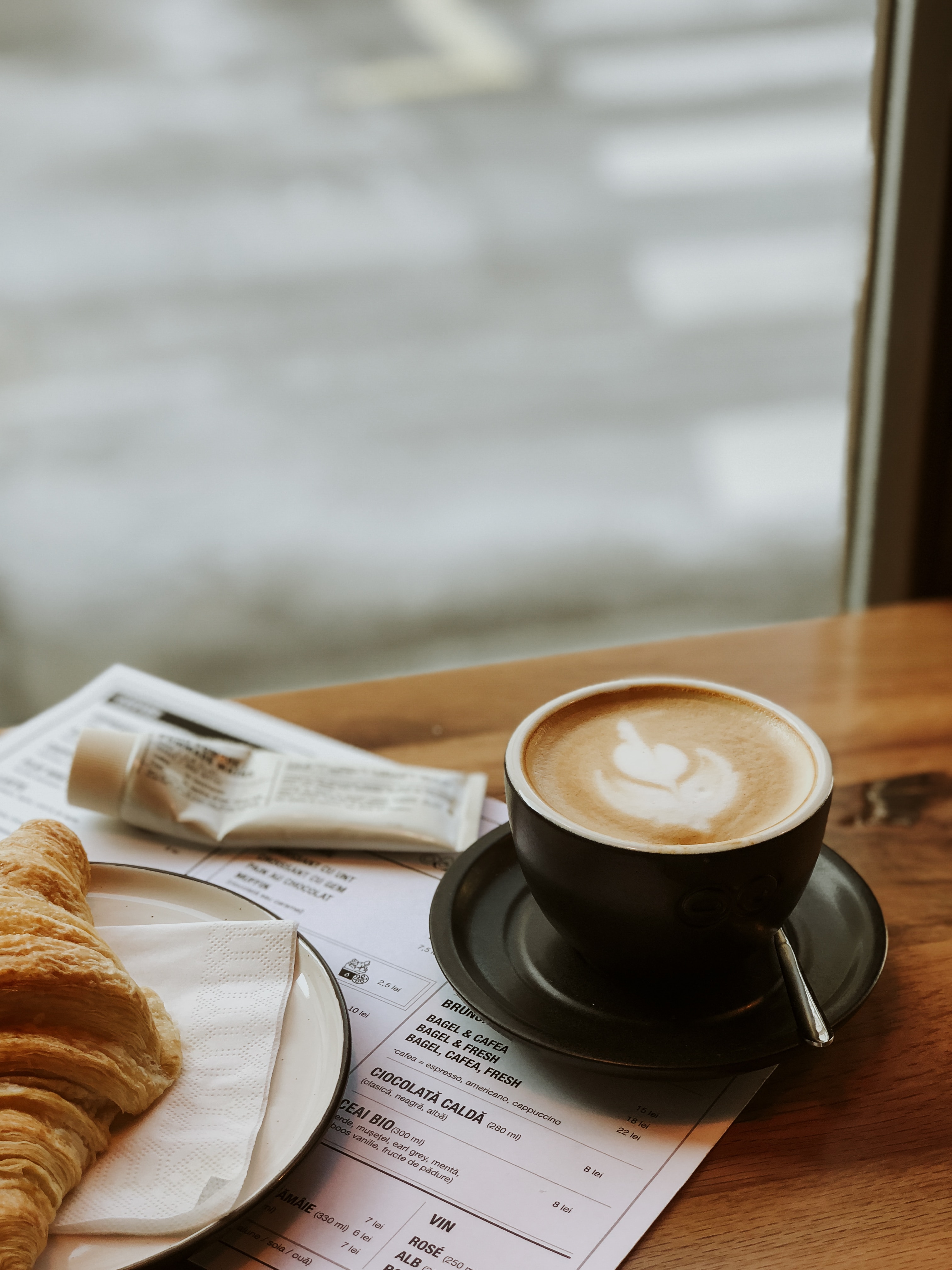 Croissant and a cup of latte on the counter by the window